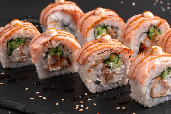 Traditional delicious fresh baked Philadelphia sushi roll set on a black background. Japanese oriental cuisine