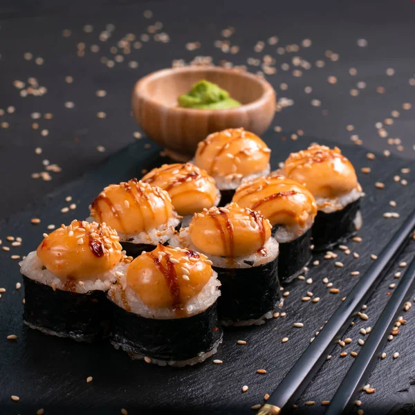 Set of baked sushi rolls with wasabi and ginger on a black background. Japanese oriental cuisin