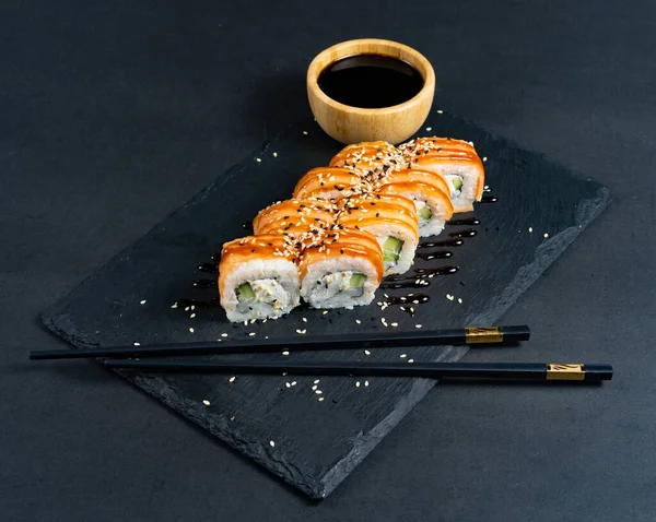 Sushi roll with cream cheese and fried salmon on dark backgroun