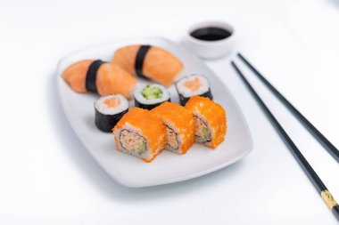 Sushi plate on white background. Makizushi. Delicious sushi rolls on white plate with chopsticks and wasabi. Maki