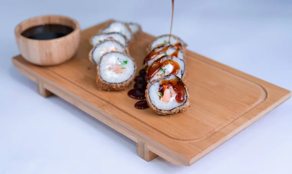 Baked sushi rolls and unagi sauce closeup. Hot fried Sushi Roll with salmon, avocado and cheese. Sushi menu.