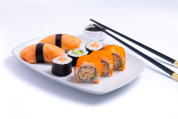 Sushi plate on white background. Makizushi. Delicious sushi rolls on white plate with chopsticks and wasabi. Maki