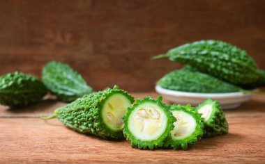 Kırsal ahşap arka planda dilimlenmiş acı kabak ya da acı salatalık. Antioksidan kaynakları açısından zengin, bazı sağlık sorunları için risklerin azaltılmasına yardımcı oluyor.