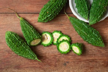 Kırsal ahşap arka planda dilimlenmiş acı kabak ya da acı salatalık. Antioksidan kaynakları açısından zengin, bazı sağlık sorunları için risklerin azaltılmasına yardımcı oluyor.