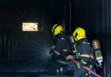 Yangın söndürücülü itfaiyeciler yüksek basınçlı su püskürterek yangını önlemek için yangınla mücadele ediyorlar..