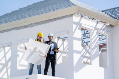 Yapı mühendisi ve planlı ustabaşı yeni ev inşaatı için çalışma planını tartıştılar.