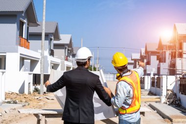 Mühendisler yeni inşaat sahasında mimari proje, mühendislik araçları ve inşaat konseptinde çalışan ve planlanan verileri tartışıyorlar..