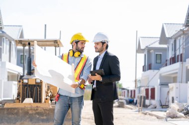 Yapı mühendisi ve planlı ustabaşı yeni ev inşaatı için çalışma planını tartıştılar.