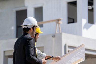 Mimarlar, şantiyedeki inşaat projesi hakkında baş mühendis ile görüştüler.