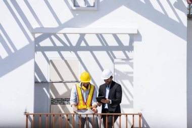 Mühendisler yeni inşaat sahasında, mühendislik araçlarında ve inşaat konseptinde mimari projeyle veri çalışması ve tablet veya dizüstü bilgisayarları tartışıyorlar..