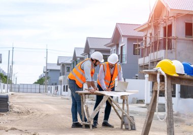 Mimarlık konsepti, mimarlar ve iş adamları inşaat sahasının planlarıyla, inşaat projesi konseptiyle çalışıyorlar..
