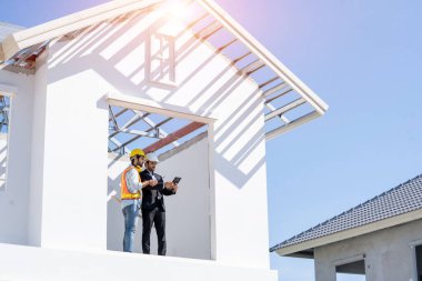 Yapı mühendisi ve planlı ustabaşı yeni ev inşaatı için çalışma planını tartıştılar.