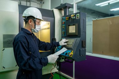 Covid-19 'a karşı koruyucu maske takan fabrika işçisi büyük bir endüstriyel fabrikada çalışıyor ve kontrol ediyor..