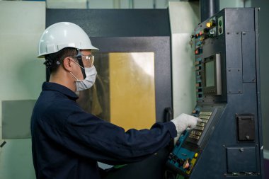 Covid-19 'a karşı koruyucu maske takan fabrika işçisi büyük bir endüstriyel fabrikada çalışıyor ve kontrol ediyor..