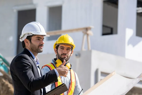The businessman or boss gives the consultant to engineer,They are consulting and solving the problems in construction site planning for new house.