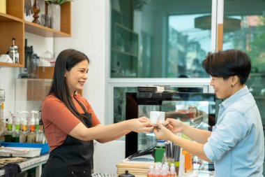 Önlüklü barista, kahve dükkanında müşterilere servis yapıyor..
