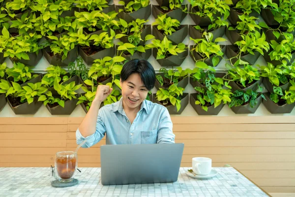 笑顔の男はノートパソコンの画面を見て 財務状況をチェックし 自宅でテーブルに座って — ストック写真
