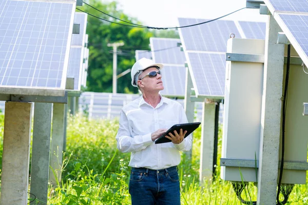 Engineer holding digital tablet working in Solar Panels Power Farm, Photovoltaic Cell Park,Innovative solution for energy solving,Green energy.