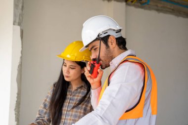 İnşaat alanında çalışan mühendis, mimarlar açık hava inşaatı projesini tartışıyor..