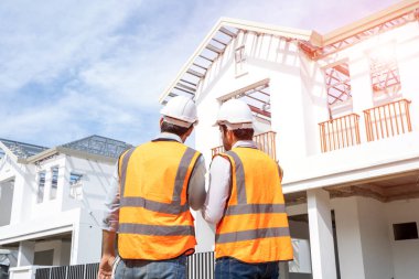 Engineer team discuss and planning from work site about construction house project with blueprint drawing paper and computer laptop.