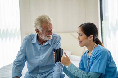 Hemşire evdeki yaşlı adama kan basıncını ölçüyor, sağlık hizmetleri kavramı, tıbbi danışman..
