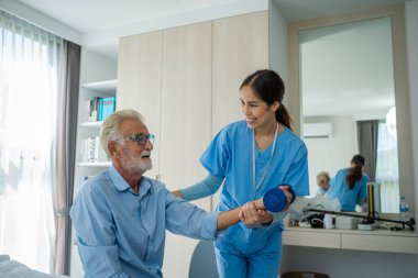 Hemşireler yaşlı bir adam için evlerinde fizik tedavi, bakım ve terapi egzersizleri yaparlar..
