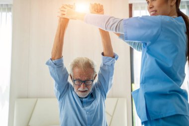 Doktor ya da hemşire kıdemli doktor, tıbbi danışman, hemşire rehabilitasyon egzersizleri ve yaşlı engelli adamla ilgilenir..