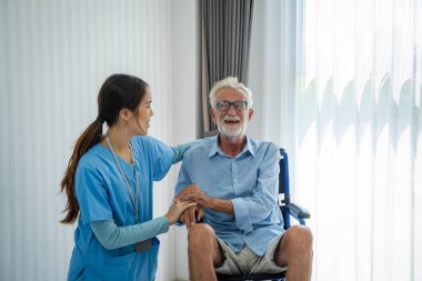 Hemşireler, tekerlekli sandalyede oturan yaşlı bir adamın sağlık sigortası konseptiyle ilgileniyor ve ona yardım ediyorlar..