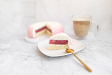 White and pink cake on a plate on a light marble table and a glass coffee mug. Background for Valentine's Day