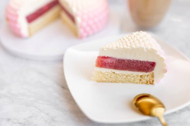 White and pink cake on a plate on a light marble table and a glass coffee mug. Background for Valentine's Day
