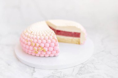 White and pink interesting beautiful cake on a white plate on a light marble table. Background for Valentine's Day