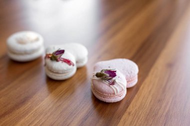 Beautiful tender delicious pastries on a wood brown background. White and pink macaroons on a table. Valentines Day background