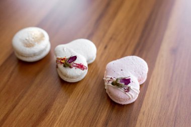Beautiful tender delicious pastries on a wood brown background. White and pink macaroons on a table. Valentines Day background
