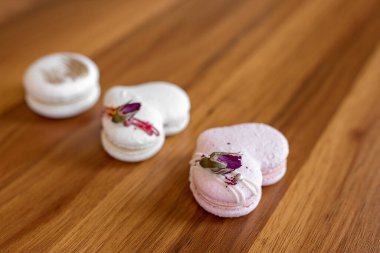 Beautiful tender delicious pastries on a wood brown background. White and pink macaroons on a table. Valentines Day background