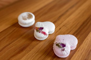 Beautiful tender delicious pastries on a wood brown background. White and pink macaroons on a table. Valentines Day background