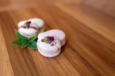 Beautiful tender delicious pastries with a green leaf on a wood brown background. White and pink macaroons on a table. Valentines Day background