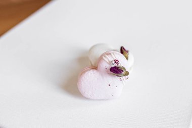 Hafif arka planda yeşil yapraklı güzel, lezzetli hamur işleri. Beyaz bir tuvalde beyaz ve pembe badem kurabiyeleri. Sevgililer Günü arkaplanı