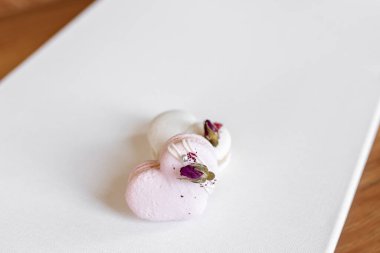 Hafif arka planda yeşil yapraklı güzel, lezzetli hamur işleri. Beyaz bir tuvalde beyaz ve pembe badem kurabiyeleri. Sevgililer Günü arkaplanı