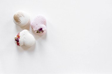 Hafif arka planda yeşil yapraklı güzel, lezzetli hamur işleri. Beyaz bir tuvalde beyaz ve pembe badem kurabiyeleri. Sevgililer Günü arkaplanı