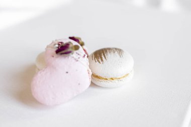 Hafif arka planda yeşil yapraklı güzel, lezzetli hamur işleri. Beyaz bir tuvalde beyaz ve pembe badem kurabiyeleri. Sevgililer Günü arkaplanı