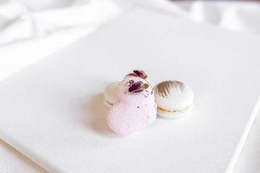 Hafif arka planda yeşil yapraklı güzel, lezzetli hamur işleri. Beyaz bir tuvalde beyaz ve pembe badem kurabiyeleri. Sevgililer Günü arkaplanı