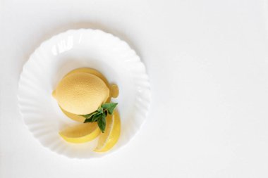 Yeşil nane yaprağı ve beyaz arka planda gerçek limon dilimleri olan limon şeklinde kremalı pasta. Lezzetli ve güzel hamur işleri. Şekerlemeler için arka plan