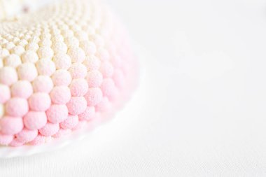 Beyaz, pembe, sıra dışı bir pasta beyaz bir tabakta, arka planda yatıyor. Lezzetli hamur işleri. Sevgililer Günü arkaplanı