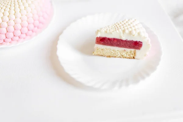 Ένα Λευκό Ροζ Κομμάτι Κέικ Βρίσκεται Ένα Λευκό Πιάτο Ένα — Φωτογραφία Αρχείου