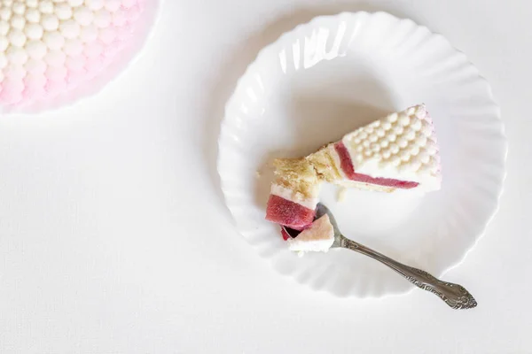 Ένα Λευκό Ροζ Κομμάτι Κέικ Βρίσκεται Ένα Λευκό Πιάτο Ένα — Φωτογραφία Αρχείου