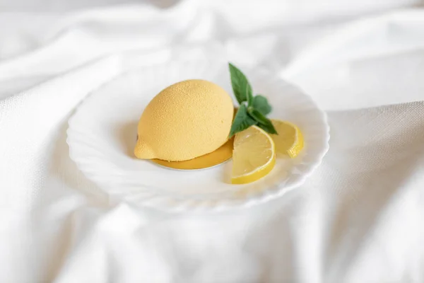 Yeşil nane yaprağı ve beyaz arka planda gerçek limon dilimleri olan limon şeklinde kremalı pasta. Lezzetli ve güzel hamur işleri. Şekerlemeler için arka plan