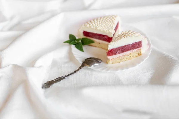 ケーキの白いピンク色の部分は 光の背景に白いプレートにあります おいしいペストリー — ストック写真