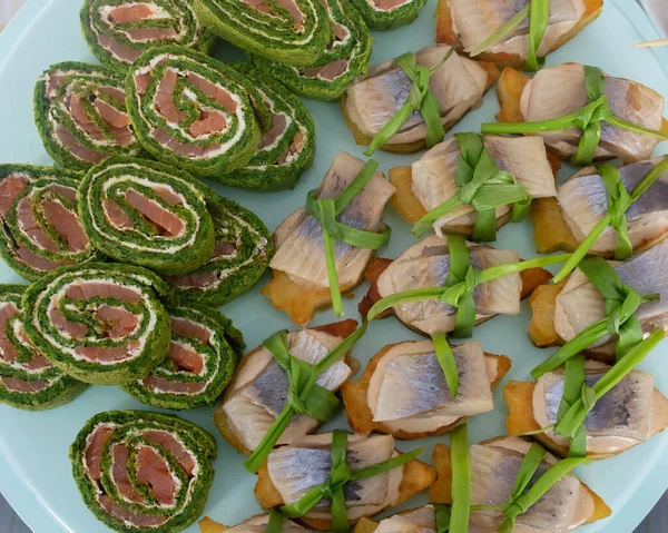 Tabakta bir sürü ringa balığı ve balık sandviçi var. Açık yeşil bir arkaplanda.