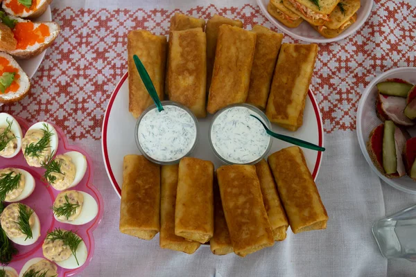 Tabakta soslu krep var. Beyaz bir masa örtüsünün arka planında.