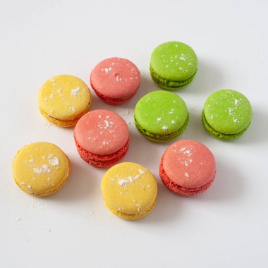 Masanın üzerinde çok renkli badem kurabiyeleri var. Beyaz arkaplanda.